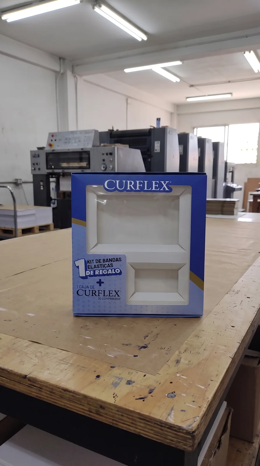 Caja impresa terminada frente a equipos de producción